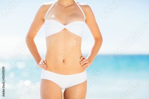 Mid section of woman in bikini standing on beach