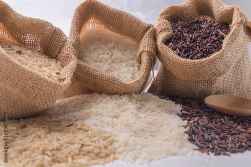 Three kinds of rice in small burlap bags on white background