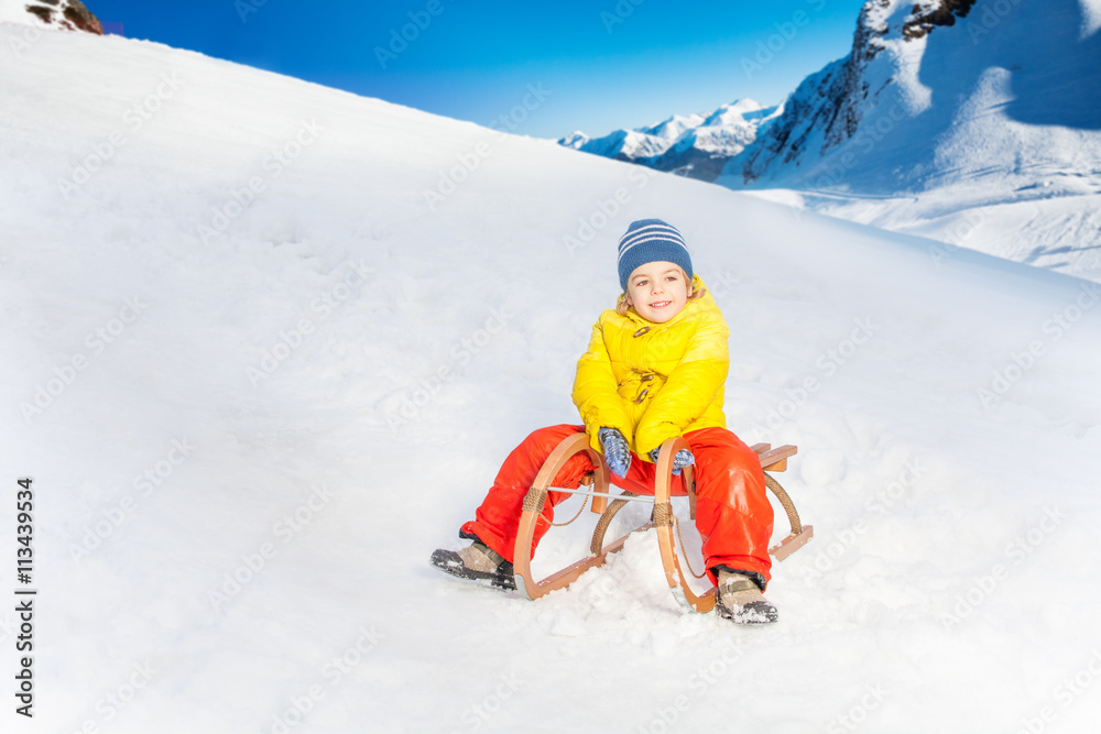 Little boy on the sledge slide down hill 