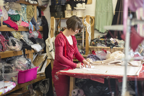 Dressmaker in Red Working on Cutting Table