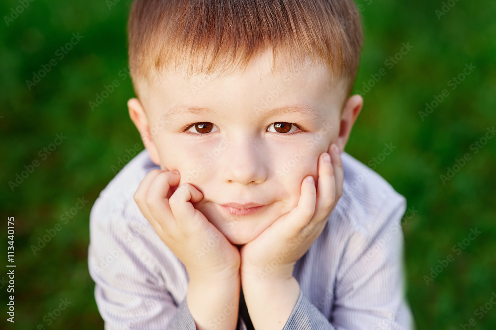 boy sits on the green grass in the summer park close up boy sits on the green grass in the summer park close up