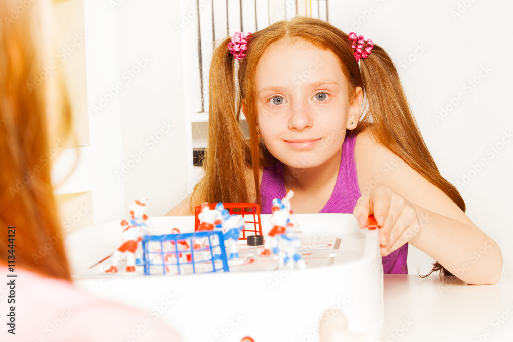 Cute girl playing ice hockey table board game Cute girl playing ice hockey table board game