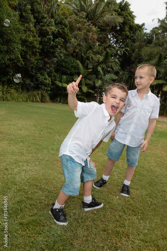 two kids in shorts and white shirts playing passionately in gard