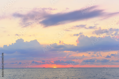 beautiful sunrise  sunset  sea. Beautiful voluminous pink clouds and sun disk above the horizon. Silhouettes of ships on the horizon in the sunset light. Beautiful sky  calm seascape. Water surface  