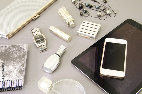 Modern woman's desktop with white smart phone, tablet, dairy and different cosmetics. Flat lay