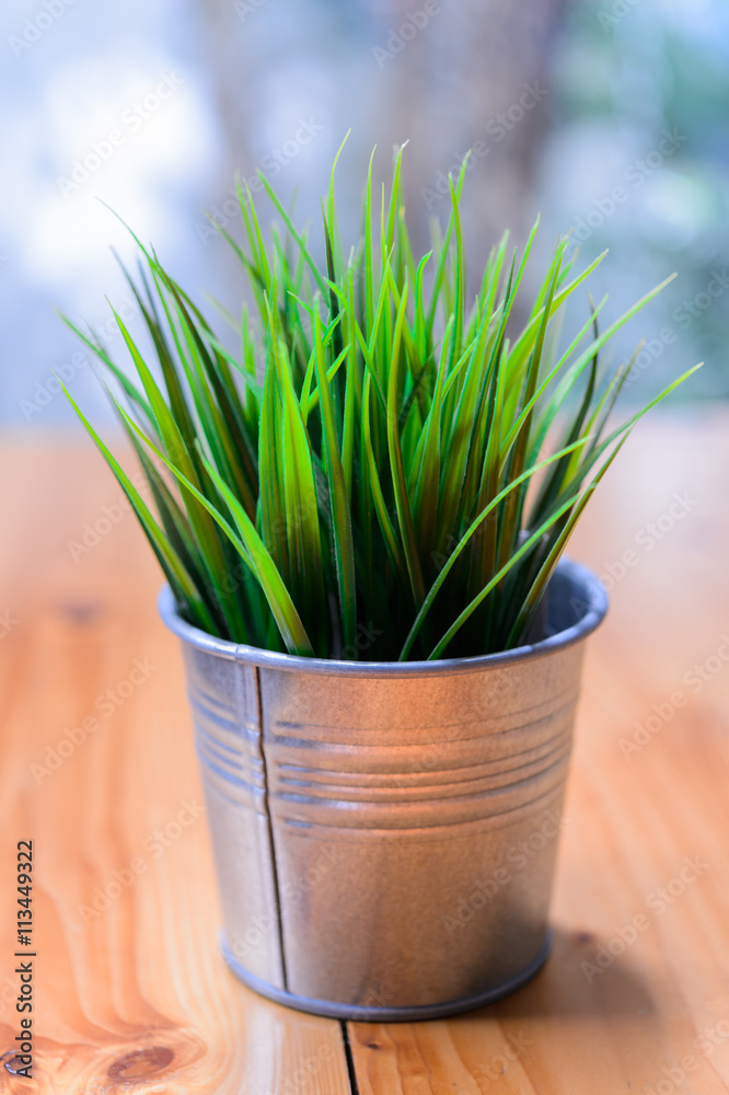 Fake grass in black pots on wooden desk