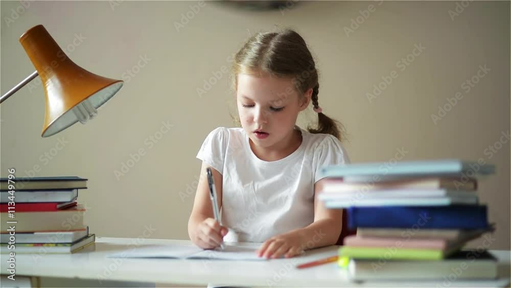 Schoolgirl doing homework and preparing for exams, cute children learning her lessons
