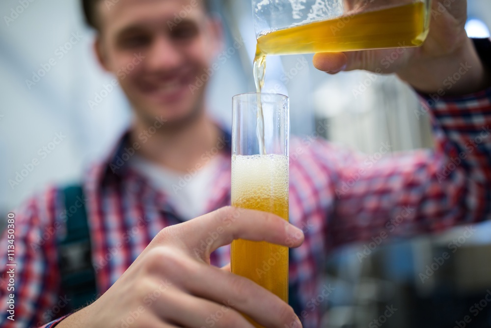 Brewer pouring beer in hydrometer cylinder Brewer pouring beer in hydrometer cylinder