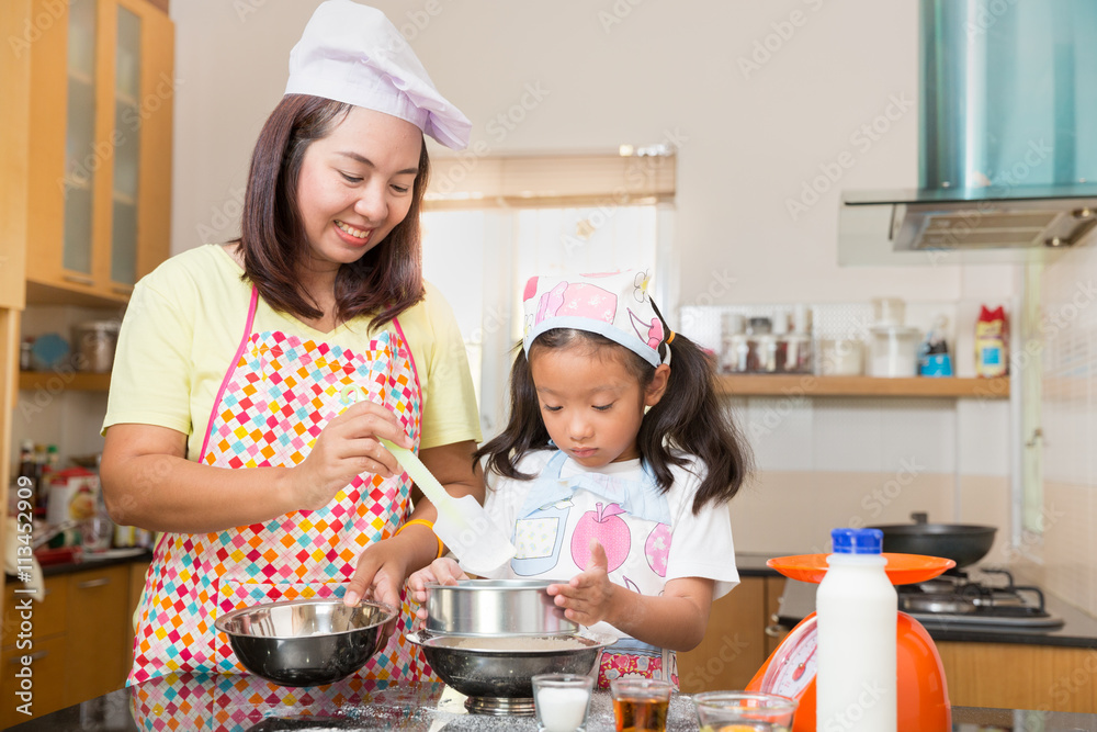 Asian mother and daughter enjoy making pancake, Asian mom teaching daughter to learn making pancake in real life kitchen at home Asian mother and daughter enjoy making pancake, Asian mom teaching daughter to learn making pancake in real life kitchen at home