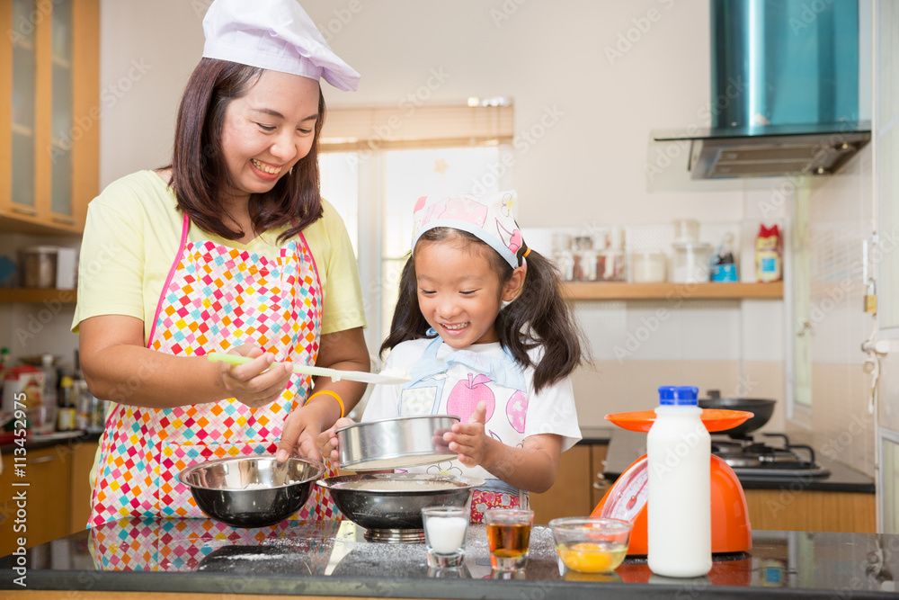 Asian mother and daughter enjoy making pancake, Asian mom teaching daughter to learn making pancake in real life kitchen at home Asian mother and daughter enjoy making pancake, Asian mom teaching daughter to learn making pancake in real life kitchen at home