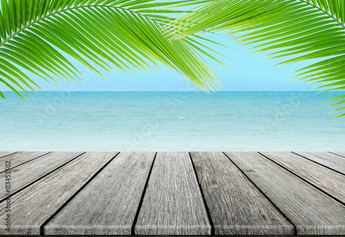 old wood table top on blurred beach background with coconut leaf