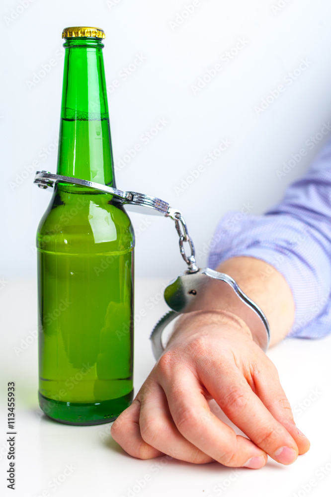 Glass of beer with handcuffs as symbol for alcohol abuse Glass of beer with handcuffs as symbol for alcohol abuse