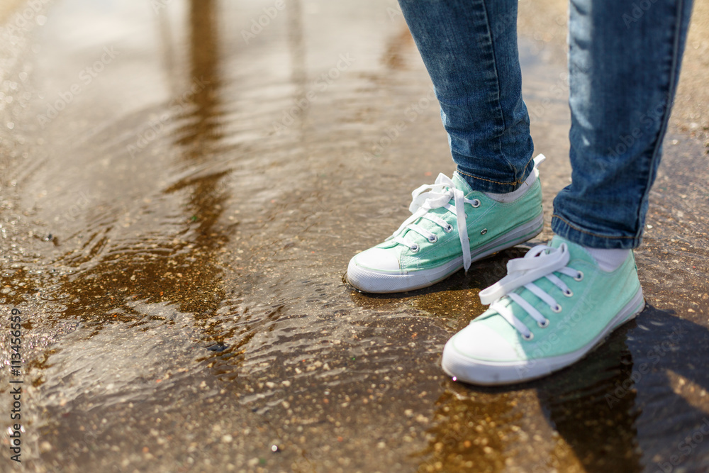 Woman in sport shoes standing in a puddle Woman in sport shoes standing in a puddle
