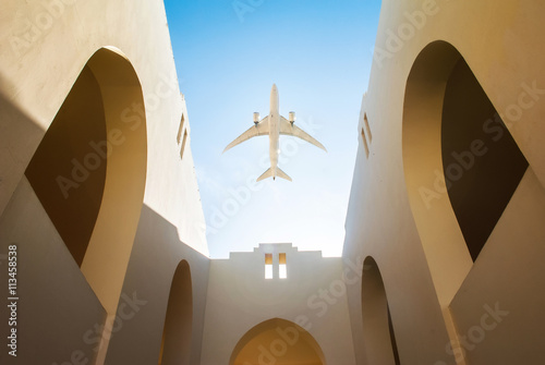Aircraft over the arabic style yard of the house with white walls and clear blue sky