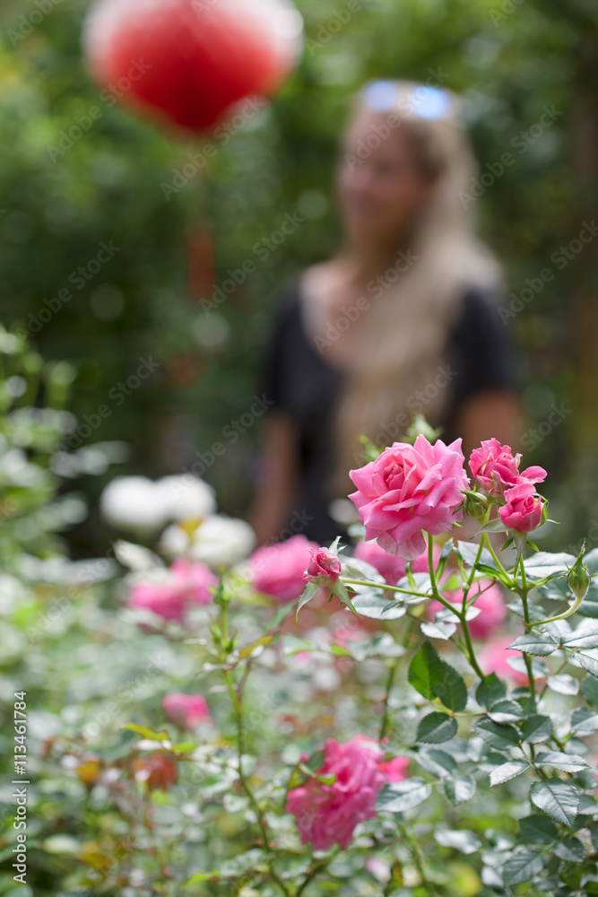 A time to love/Photo of rose on the background of the garden, where stands a beautiful blonde girl...