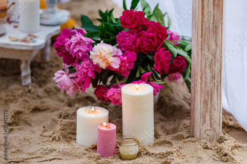 Beautiful  delicate wedding decorations with candles and fresh flowers on the beach