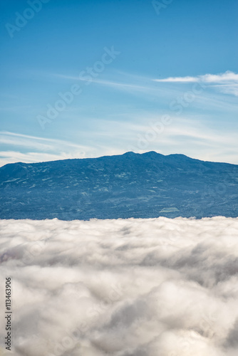Barva volcano and near mountain ranges in the central valley of Costa Rica seen above the clouds that completly cover the city of San Jose the during the morning