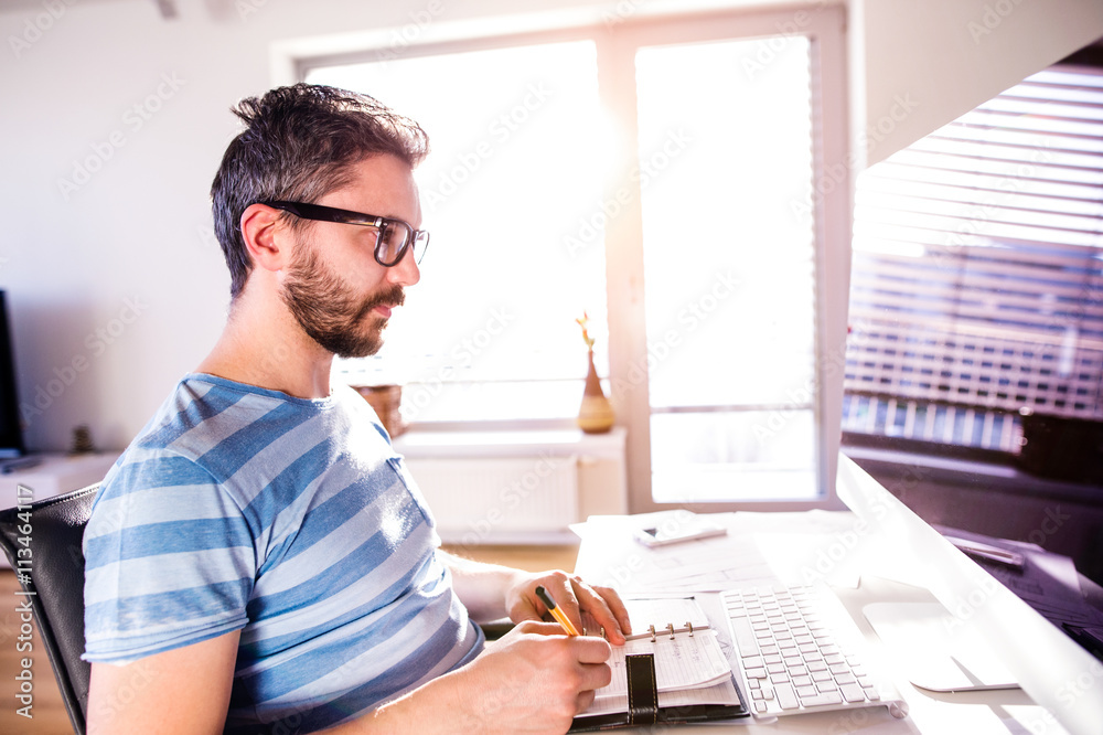 Architect working from home on computer, writing, taking notes Architect working from home on computer, writing, taking notes