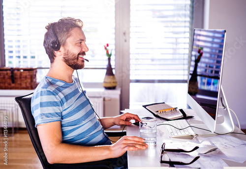 Man sitting at desk working from home on computer photo
