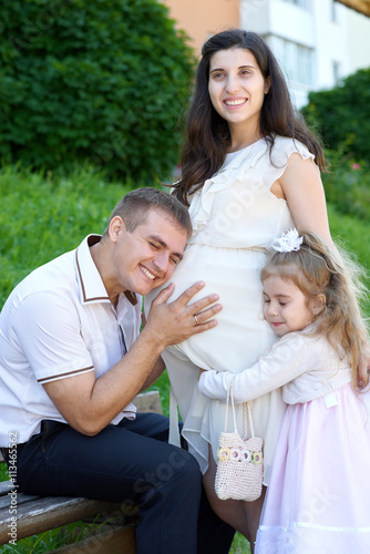 man and child listen belly of pregnant woman, happy family, couple in city park, summer season, green grass and trees © soleg
