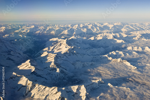 Snowy mountains rise above the clouds. High altitude view.