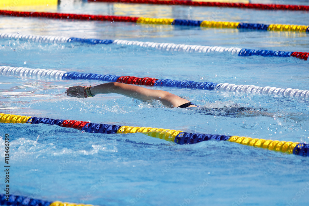 Nadador nadando crol en piscina de verano. Competición de natación. Estilo olímpico. Nadadora compitiendo a estilo libre.