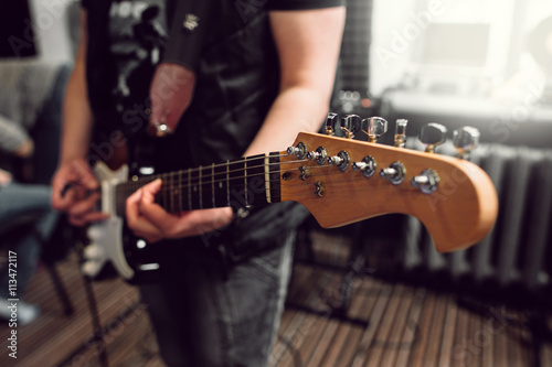 Bass guitar in playing musician hands close-up. Focus on bass guitar neck in player hands. Unrecoginzable bass guitar player performing at music studio, blurred background