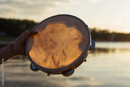 музыкальный инструмент бубен или пандейру на фоне неба в закате photo