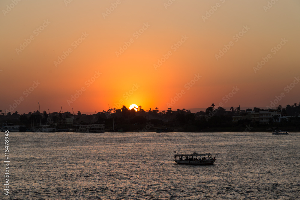 Naklejka premium Tourist boat at Luxor waterfront during sunset.