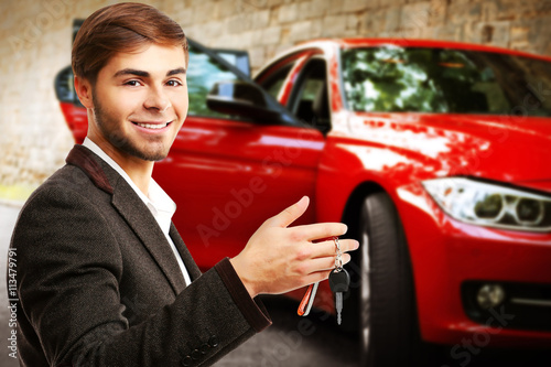 Businessman holding car key on blurred red car background