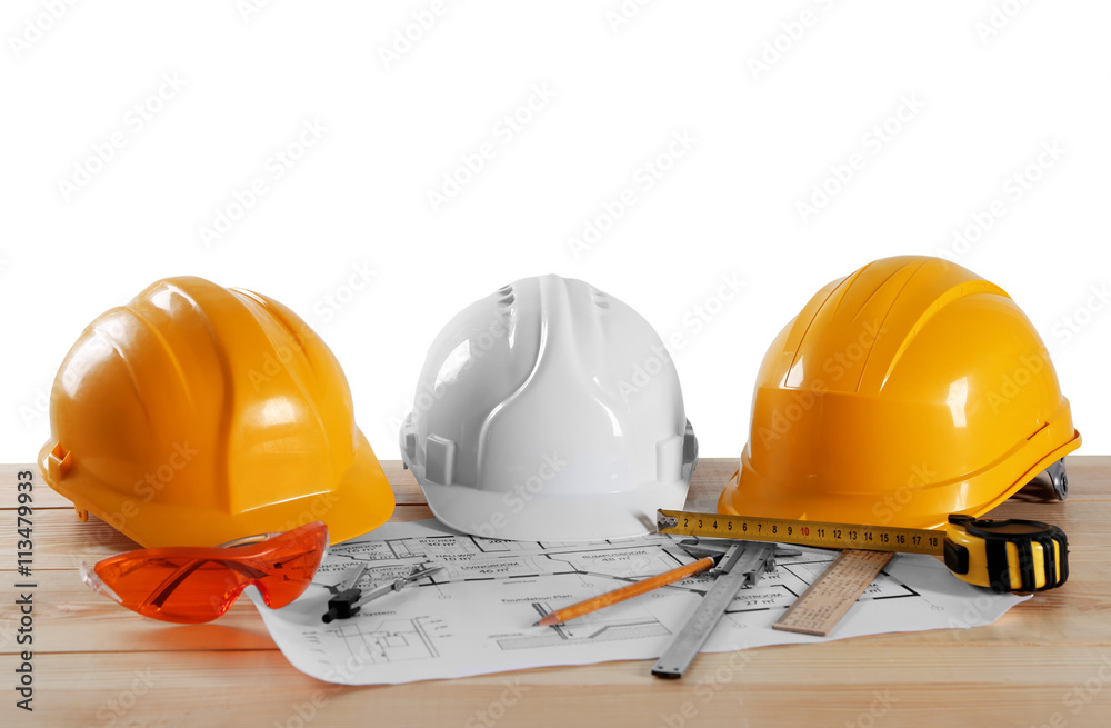 Construction drawings with tools on wooden table isolated on white background Construction drawings with tools on wooden table isolated on white background