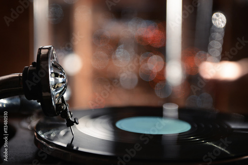 Turntable with vinyl record on dark blurred background