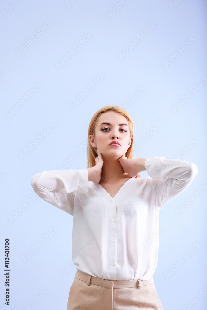 Beautiful blonde young woman in white shirt and beige pants on blue wall background Beautiful blonde young woman in white shirt and beige pants on blue wall background