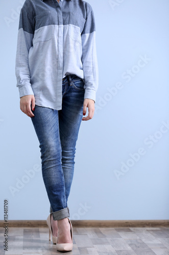 Beautiful young woman in shirt and jeans on blue wall background