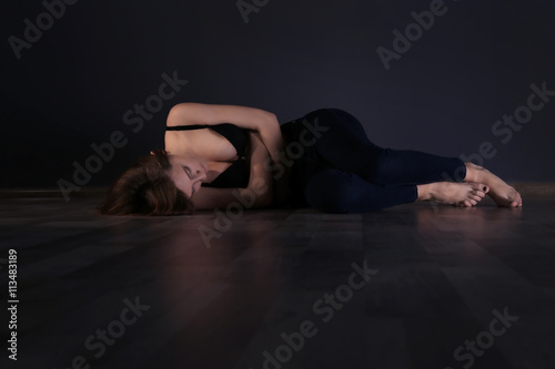 Anorexic girl lying on the floor on dark wall background