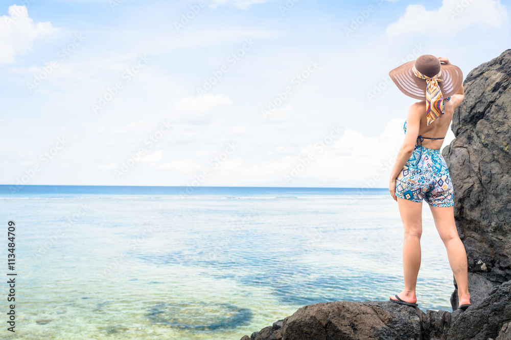 Wunschmotiv: Frau steht auf Felsen am Strand und blickt aufs Meer mit Fernweh #113484709