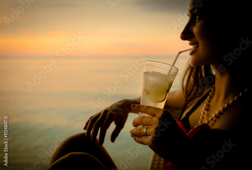 Frau im Sommer Urlaub trinkt Cocktail zum Sonnenuntergang photo