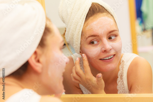 Woman applying mask cream on face in bathroom