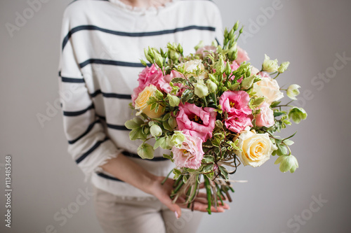 Rich bunch of pink eustoma and roses flowers, green leaf in hand Fresh spring bouquet. Summer Background.