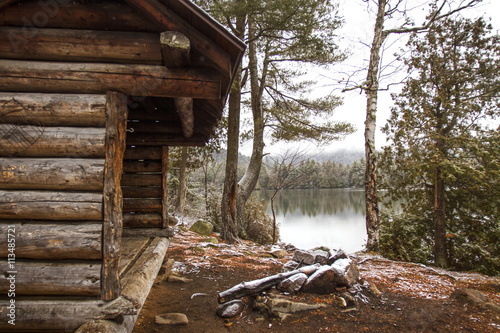 Old log cabin by lake and trees in forest