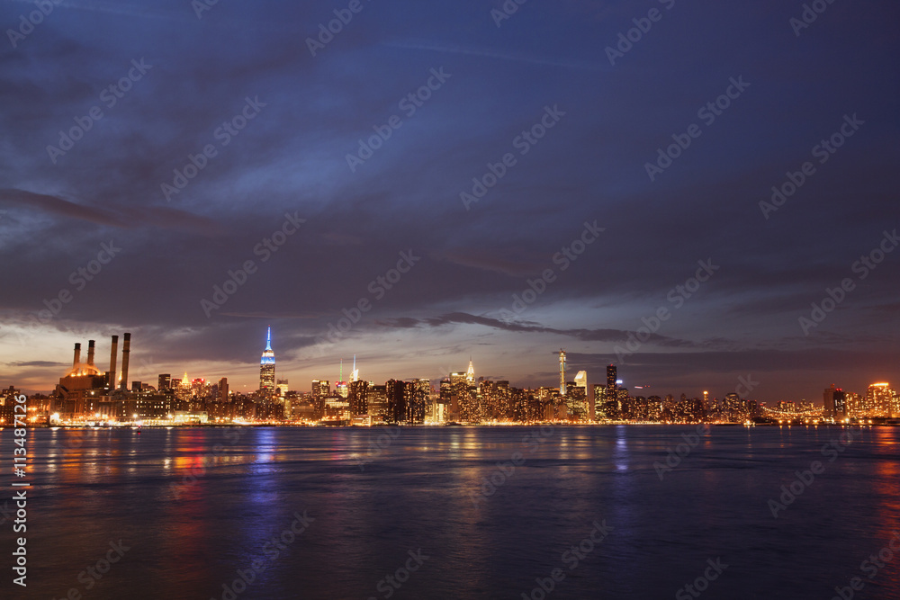 Scenic view of river and illuminated cityscape against cloudy sky at night Scenic view of river and illuminated cityscape against cloudy sky at night