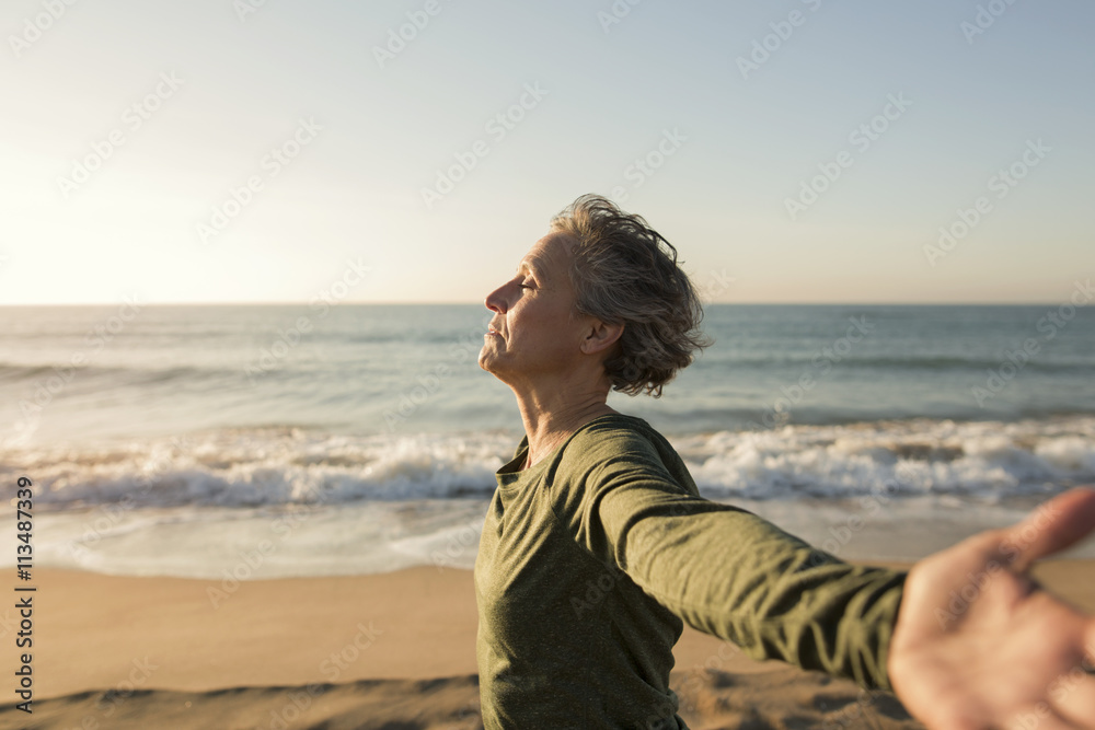 Mature woman with arms outstretched standing on beach Mature woman with arms outstretched standing on beach