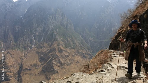 Woman walking on hike trail of Tiger Leaping Gorge which is one of the deepest gorges with spectacular sceneries on the planet and has the best hiking trail in the China. 