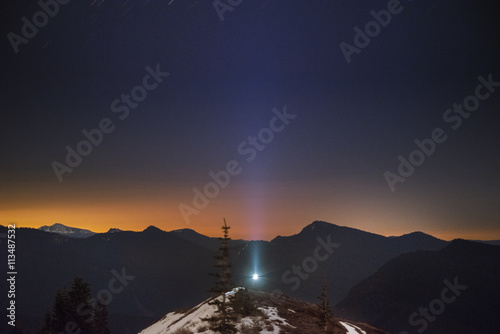 Blue light on hill against silhouette mountain range during sunset