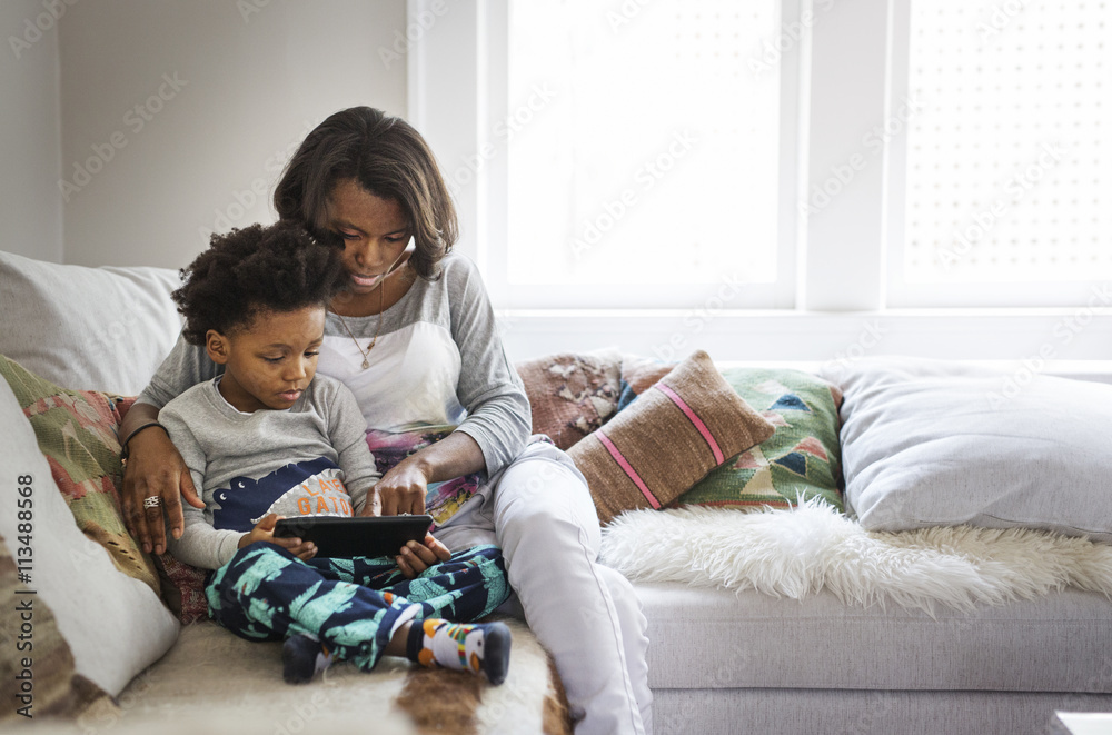 Mother and son using digital tablet while sitting on sofa at home Mother and son using digital tablet while sitting on sofa at home