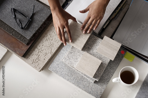 Overhead view of interior designer examining tiles at desk in office photo
