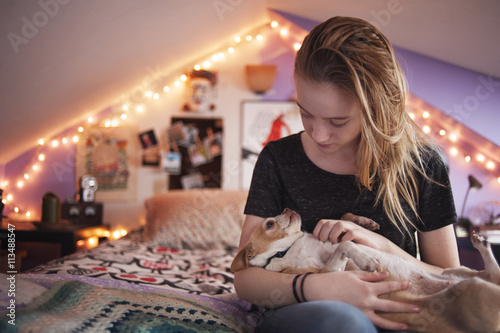 Girl holding her dog while sitting on bed at home photo