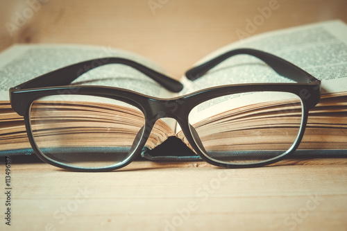 Old books and glasses on a wooden table with filter effect retro