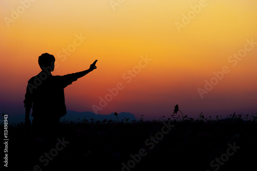 Silhouette of man posing at sunset sky background.