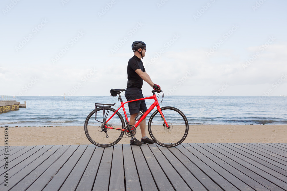 Man standing with bike looking at view of a Melbourne beach